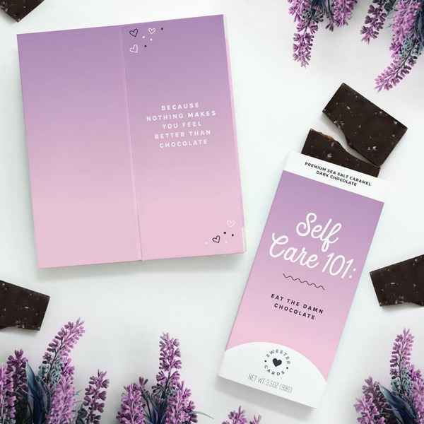 The image shows a chocolate bar with a purple and pink gradient packaging labeled 'Self Care 101: Eat The Damn Chocolate'.